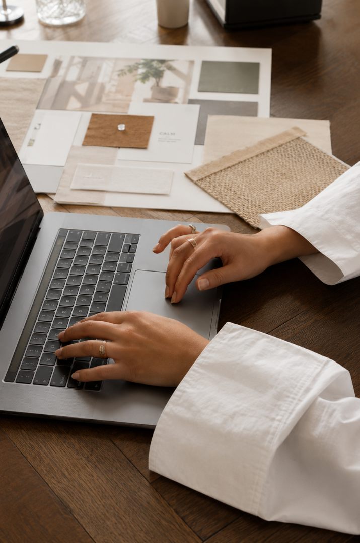 Designer working on a laptop beside a board of material and fabric samples